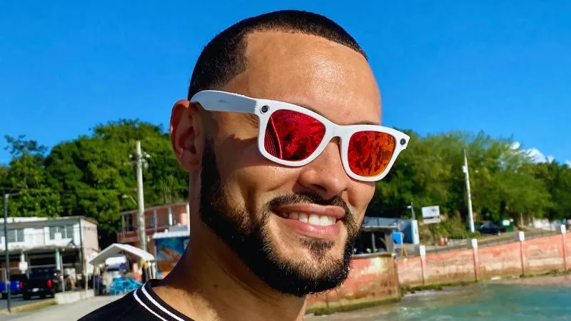 Hombre usando gafas inteligentes W610 en exterior, con lentes rojos reflectivos, probadas en uso real durante el día